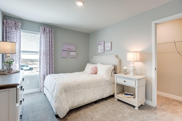 carpeted bedroom with a walk in closet, a closet, and a textured ceiling