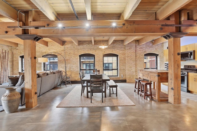 dining space featuring beamed ceiling, concrete floors, wooden ceiling, and brick wall