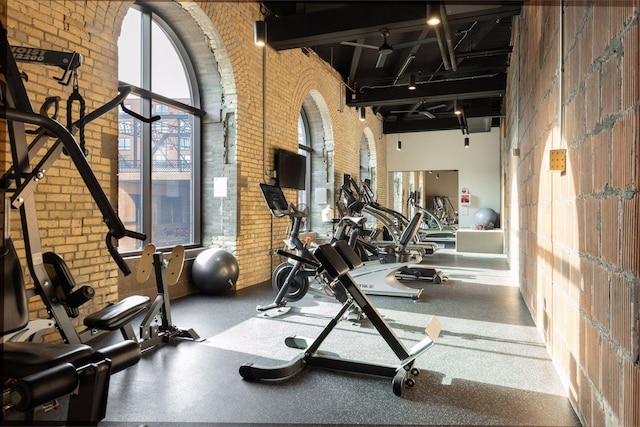 exercise room featuring a high ceiling and brick wall