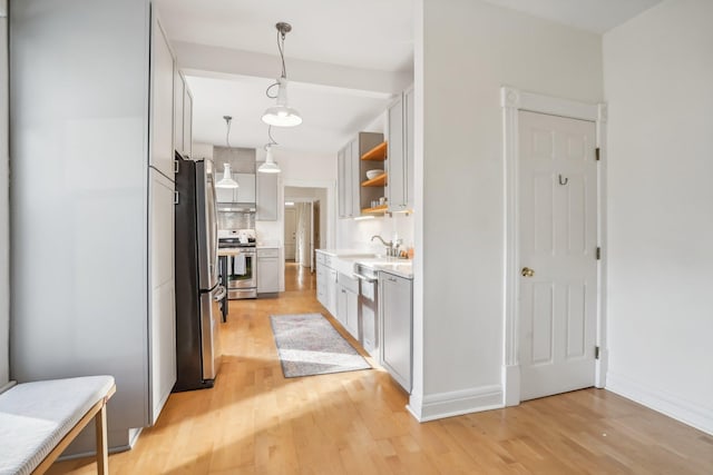 kitchen with sink, hanging light fixtures, light wood-type flooring, appliances with stainless steel finishes, and tasteful backsplash