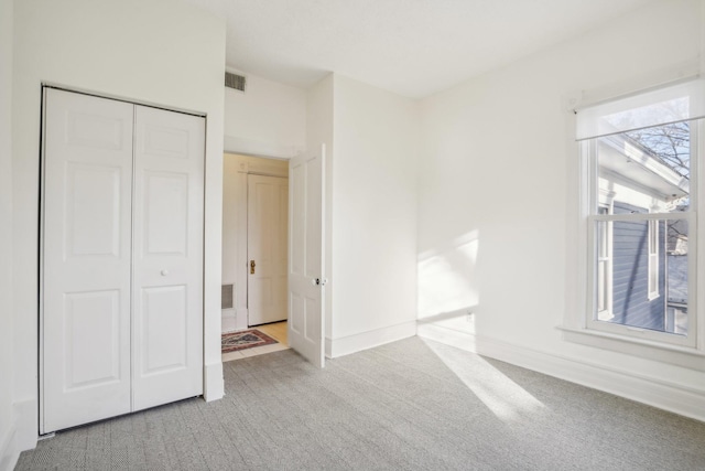 unfurnished bedroom featuring a closet and light colored carpet