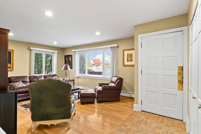 living room with a baseboard heating unit, light wood-style flooring, and recessed lighting