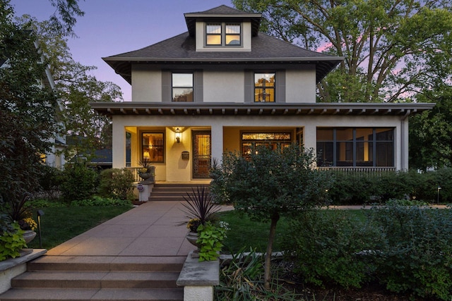 view of front of home with a porch, roof with shingles, and stucco siding