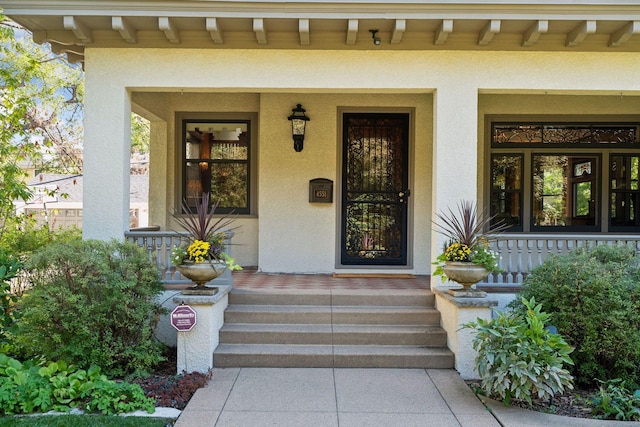 doorway to property with a porch and stucco siding