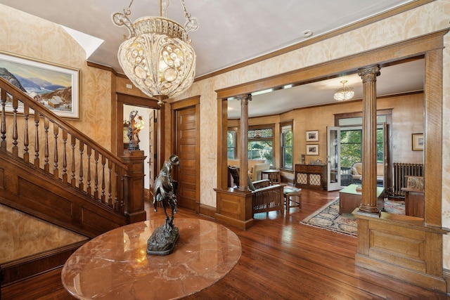 entryway with ornate columns, crown molding, a chandelier, and hardwood / wood-style floors