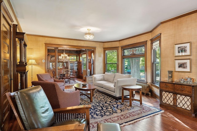 living room featuring radiator, crown molding, and an inviting chandelier