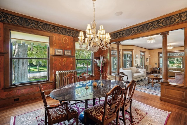 dining space with radiator, ornate columns, ornamental molding, and wood finished floors