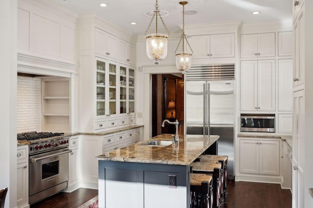 kitchen featuring white cabinets, high quality appliances, glass insert cabinets, light stone countertops, and a sink