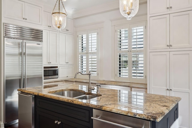 kitchen featuring white cabinetry, stainless steel appliances, a sink, and decorative light fixtures