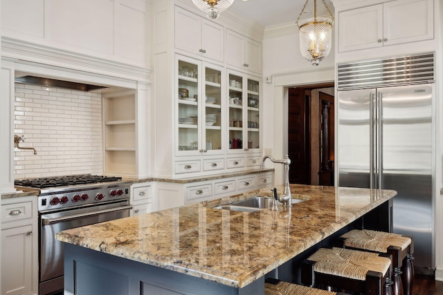 kitchen featuring high quality appliances, glass insert cabinets, crown molding, white cabinetry, and a sink