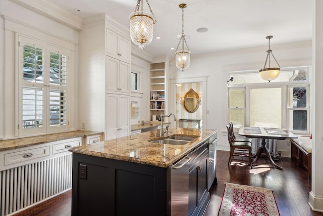 kitchen with dark wood finished floors, ornamental molding, hanging light fixtures, white cabinetry, and a sink