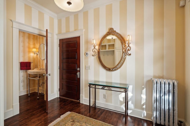 foyer featuring crown molding, wood finished floors, baseboards, radiator, and wallpapered walls