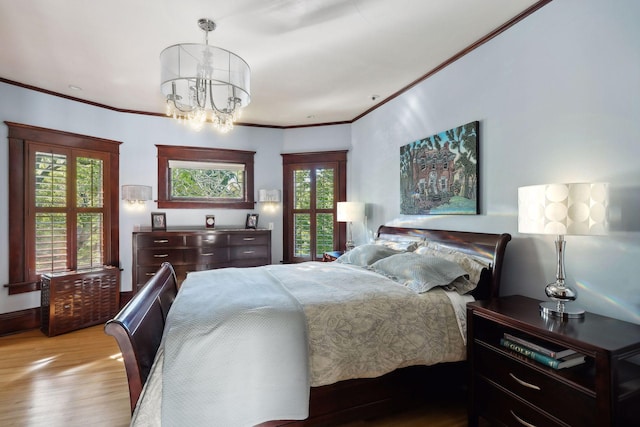 bedroom with a notable chandelier, crown molding, baseboards, and wood finished floors