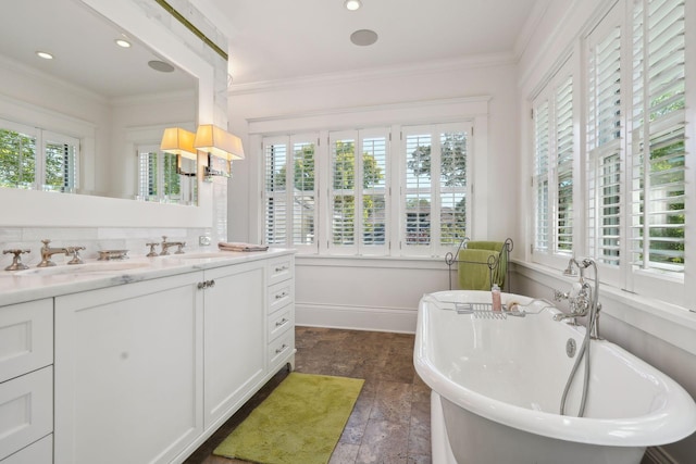 full bath featuring baseboards, crown molding, vanity, and a freestanding bath