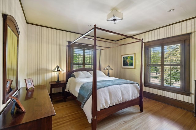 bedroom with wood finished floors and crown molding