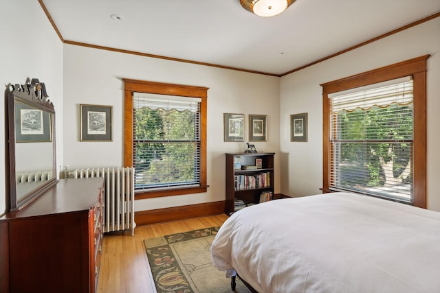 bedroom with ornamental molding, multiple windows, light wood-type flooring, and radiator