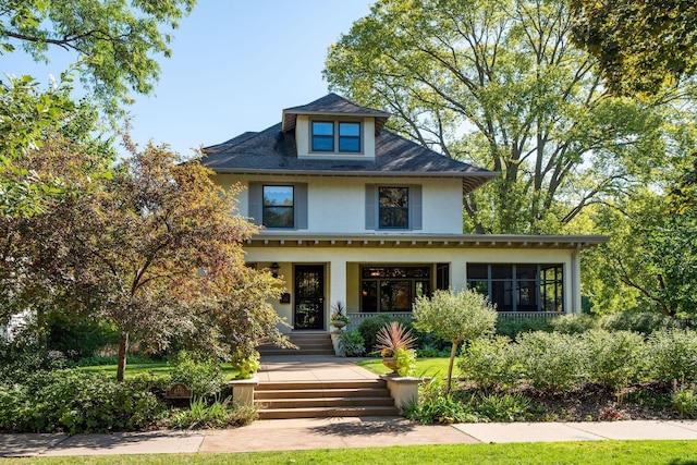 american foursquare style home with covered porch and stucco siding