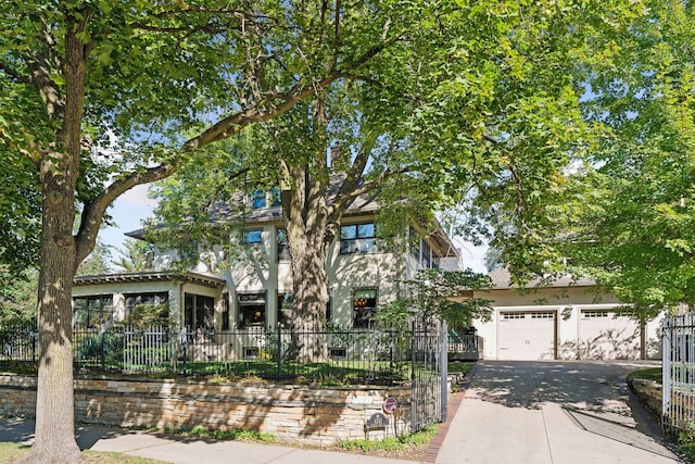 view of front facade with a fenced front yard, aphalt driveway, a garage, and stucco siding