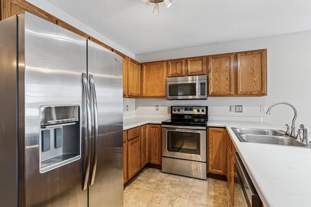 kitchen with sink, a textured ceiling, and appliances with stainless steel finishes