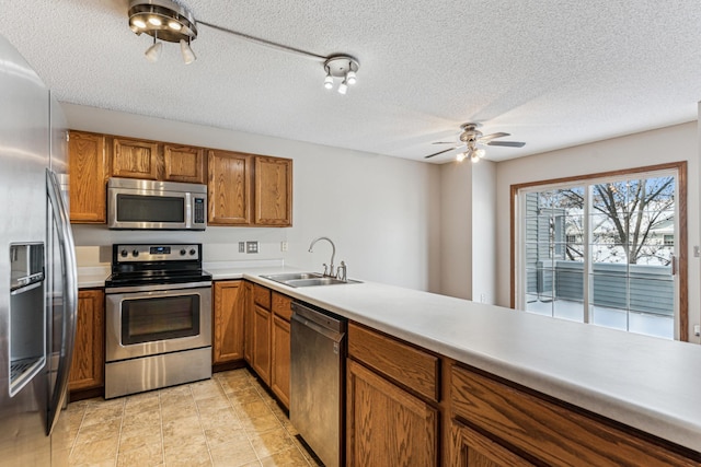 kitchen featuring kitchen peninsula, ceiling fan, appliances with stainless steel finishes, a textured ceiling, and sink