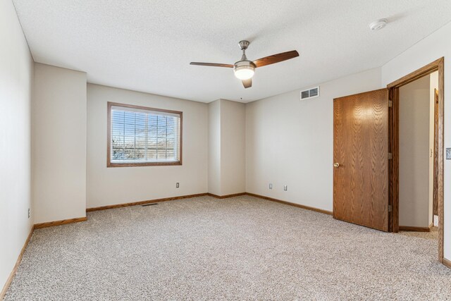 carpeted spare room featuring ceiling fan and a textured ceiling