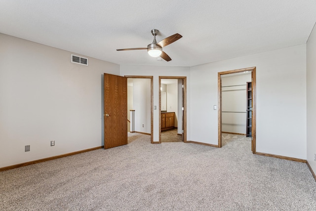 unfurnished bedroom featuring a spacious closet, ceiling fan, a closet, and light carpet