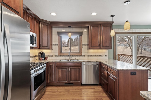 kitchen with a peninsula, appliances with stainless steel finishes, plenty of natural light, and a sink