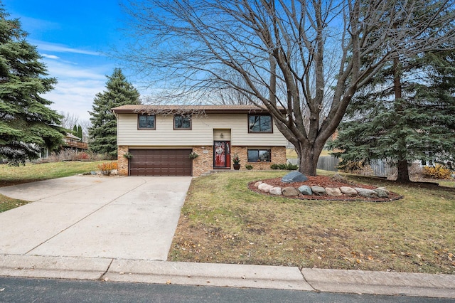 raised ranch with driveway, brick siding, and a front lawn