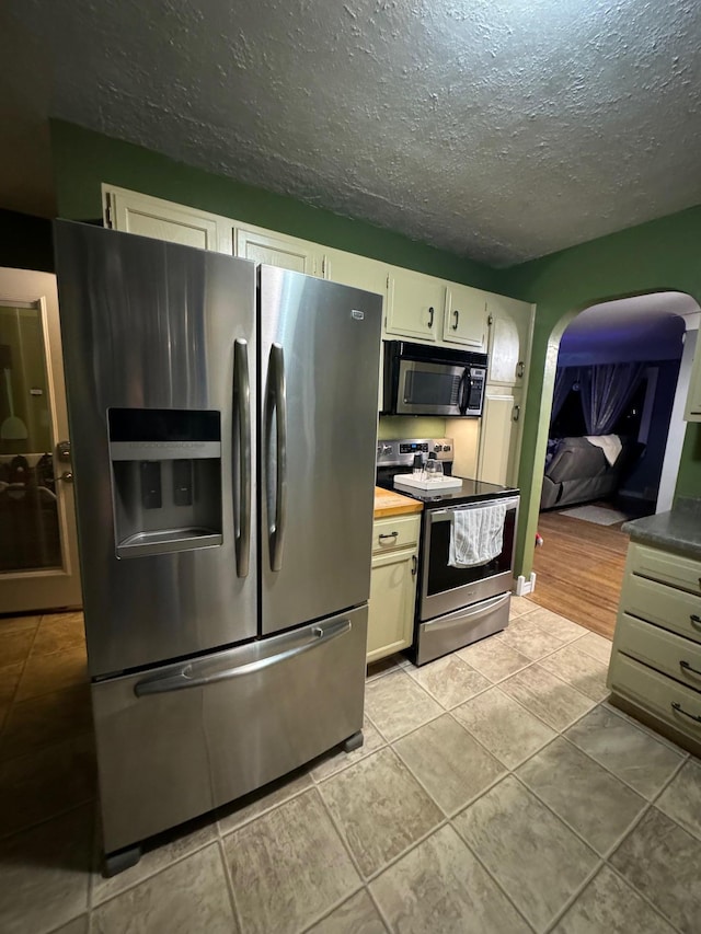 1630 3rd St N, Fargo, ND 58102 - kitchen featuring stainless steel appliances, arched walkways, a textured ceiling, light tile patterned flooring, and white cabinets