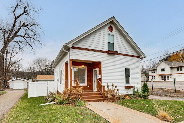 bungalow-style house featuring a garage, an outbuilding, and a front yard