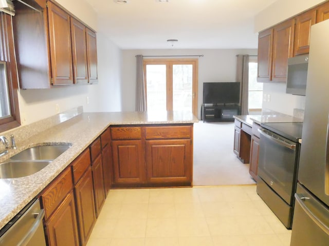 kitchen with kitchen peninsula, sink, light colored carpet, and stainless steel appliances