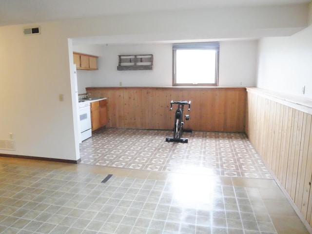 kitchen with white range oven, wood walls, and light tile patterned flooring