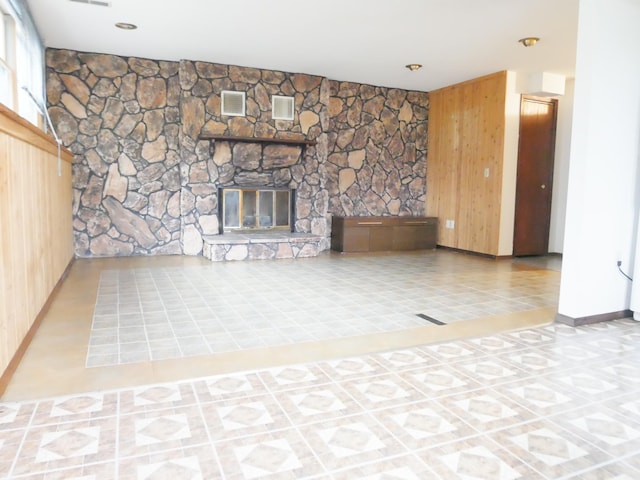 unfurnished living room with wooden walls, a fireplace, and light tile patterned floors