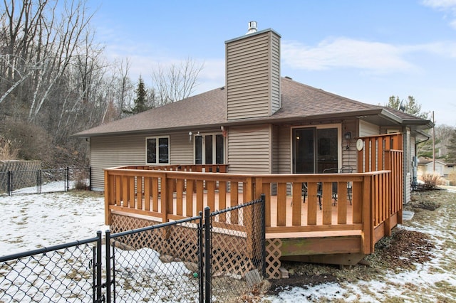 snow covered rear of property with a wooden deck