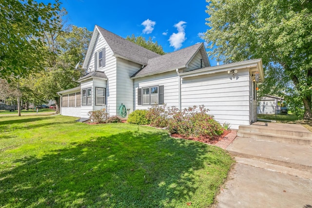 view of home's exterior with a sunroom, a lawn, and roof with shingles