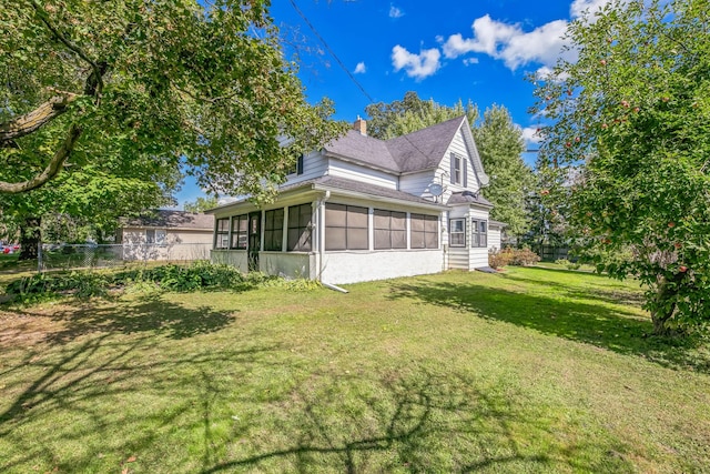 view of property exterior with a sunroom, a chimney, fence, and a yard