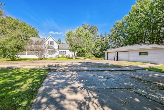 exterior space with a detached garage, a front lawn, and an outbuilding