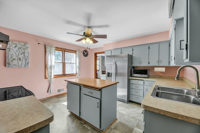 kitchen with a center island, visible vents, appliances with stainless steel finishes, a ceiling fan, and a sink