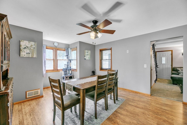 dining room with a ceiling fan, baseboards, visible vents, and light wood finished floors