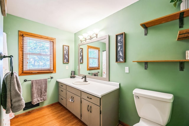 bathroom with plenty of natural light, vanity, toilet, and wood finished floors