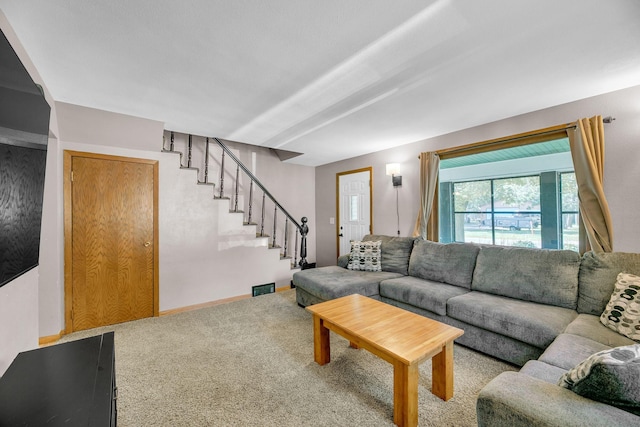 carpeted living room with stairs, visible vents, and baseboards