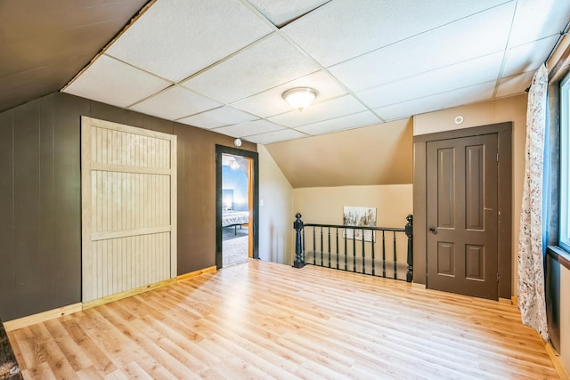 bonus room with vaulted ceiling, wood walls, and wood finished floors