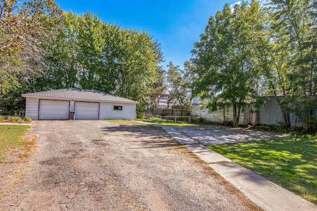 exterior space featuring a detached garage, fence, and an outdoor structure