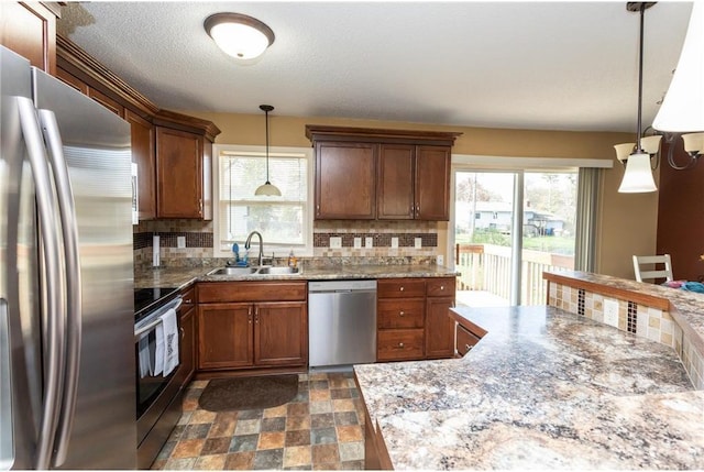 kitchen with decorative light fixtures, stainless steel appliances, tasteful backsplash, and sink