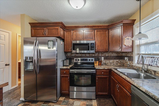 kitchen featuring sink, hanging light fixtures, tasteful backsplash, a textured ceiling, and appliances with stainless steel finishes