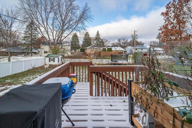 snow covered deck with a trampoline and a storage unit