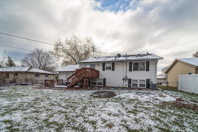 snow covered back of property with central AC and a wooden deck