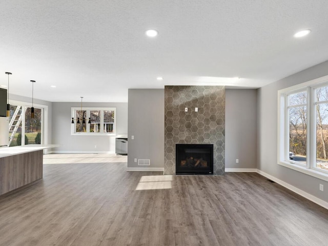 unfurnished living room with hardwood / wood-style floors, a large fireplace, and a textured ceiling