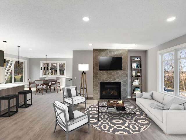 living room with a stone fireplace, wood-type flooring, and a textured ceiling