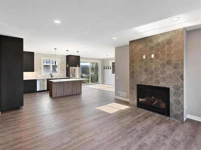 unfurnished living room featuring sink, wood-type flooring, and a fireplace